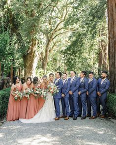 a group of people standing next to each other in front of some trees and bushes