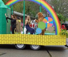 people are riding on the back of a float with animals and rainbows in it