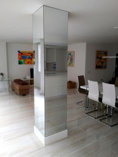 an empty room with white chairs and a glass partition in the middle that is reflecting light