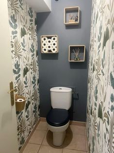 a toilet in a bathroom with wallpaper on the walls and decorative decorations above it