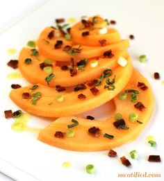 sliced pieces of fruit on a white plate with green and brown confetti sprinkles