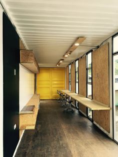 an empty conference room with wooden benches and yellow partitions on the wall behind them