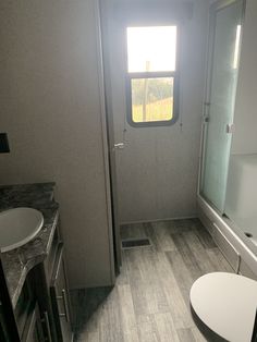 a bathroom with a toilet, sink and shower stall in the corner next to a window