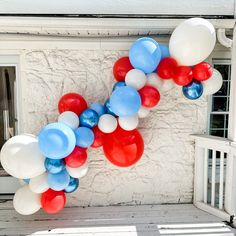 red, white and blue balloons are hanging from the side of a house in front of a window