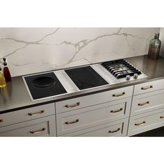 a stove top oven sitting on top of a counter next to white drawers and cabinets