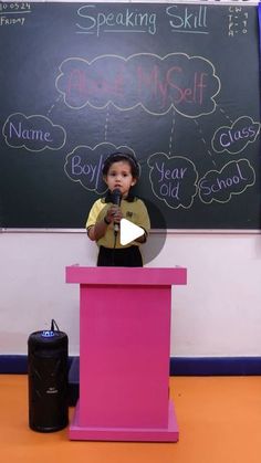 a young boy standing at a podium in front of a blackboard