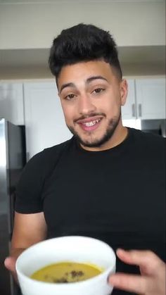 a man is holding a bowl of soup in his hand and smiling at the camera