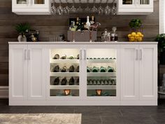 a white cabinet filled with lots of bottles and glasses next to a counter topped with wine glasses