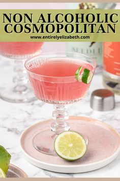 a pink drink in a glass with lime on the rim