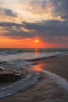 the sun is setting over the ocean with waves