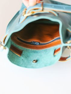 a hand holding a blue purse on top of a white table