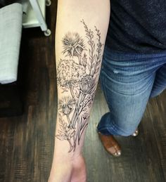 a woman's arm with flowers and plants tattooed on the left side of her body