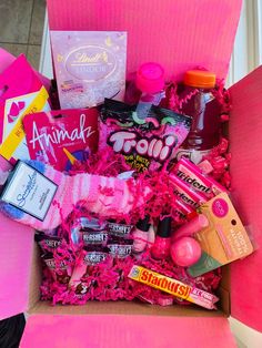 a pink box filled with lots of different types of candy and other things in it