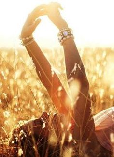 a woman laying in the grass with her hands on her head and arms behind her head