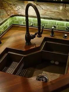 a kitchen sink and faucet with green tiles on the wall