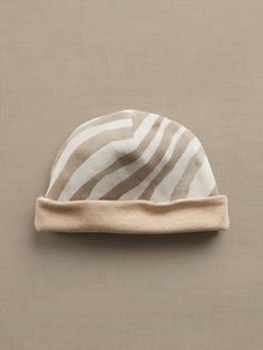 a brown and white striped hat sitting on top of a beige table next to a wall