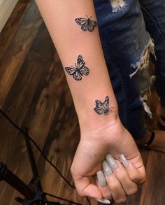 a woman's arm with three butterflies on it and one is holding the other hand