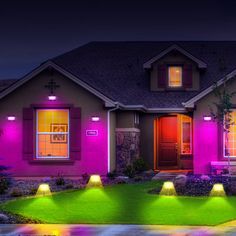 a house that has some lights on in front of it and the grass is green