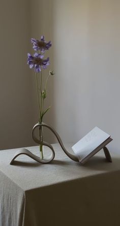 a vase with flowers in it sitting on a table next to a book and a pen