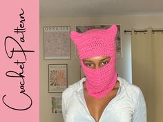 a woman wearing a pink crocheted cat mask