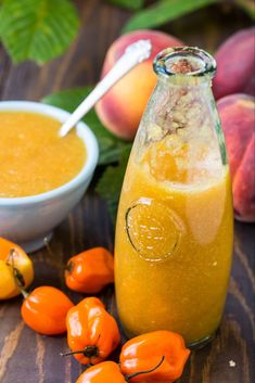 a glass bottle filled with liquid next to some peaches and other fruit on a table