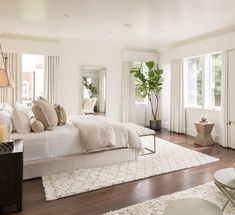 a large bedroom with white walls and wooden floors, along with two couches on either side of the bed