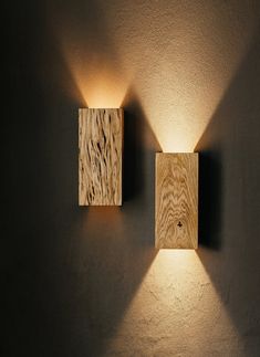 two square wooden lights mounted to the side of a wall in a dimly lit room