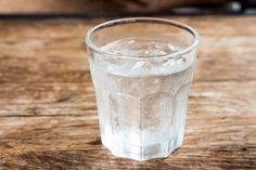 a glass filled with water sitting on top of a wooden table