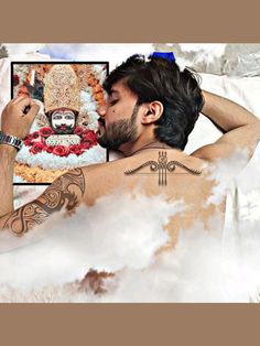 a man with tattoos on his chest and arms is laying down in front of a cake