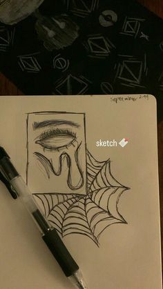 a pen is sitting on top of a notebook with a drawing of a spider web