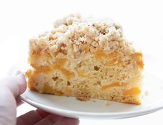 a piece of cake on a white plate being held by a person's hand