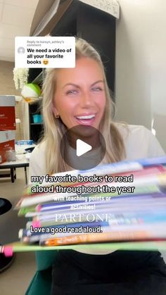 a woman is holding up some books in her hand and smiling at the camera while talking to someone else