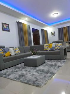 a living room with grey couches, yellow and gray pillows, and blue lights