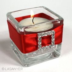 a candle that is inside of a glass container with a red ribbon around the edge