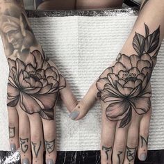 two hands that have flowers on them and tattoos on their palms, both with numbers