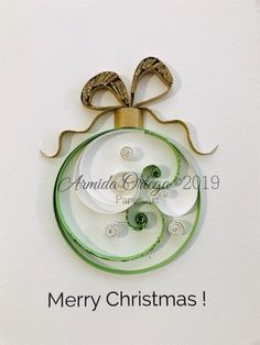 an ornament is hanging on the wall in front of a white background with green ribbon