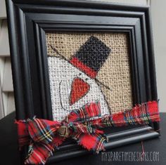 an image of a snowman with a red bow on it's head, framed in black frame