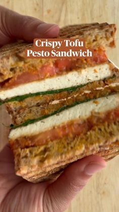 a person holding a sandwich in their hand with the words crispy tofu pesto sandwich on it