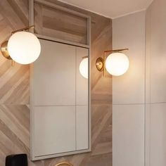 a bathroom vanity with two lights and a mirror on the wall next to it's sink