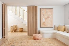 a living room filled with furniture and a painting on the wall next to a stair case