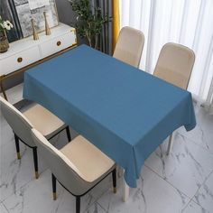 a blue table cloth on top of a dining room table with four chairs and a dresser in the background