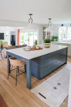 a large kitchen island in the middle of a living room with chairs and rugs on the floor