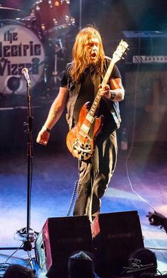 a man standing on top of a stage holding a guitar