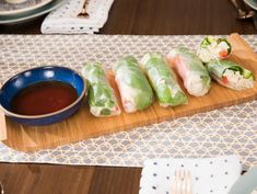 a wooden tray topped with rolls and dipping sauce