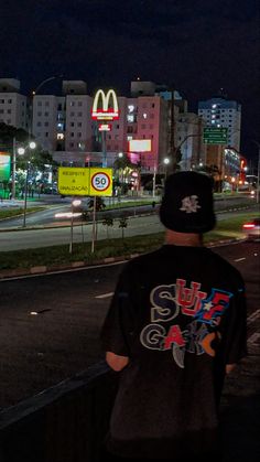 a man standing on the side of a road next to a mcdonalds sign at night