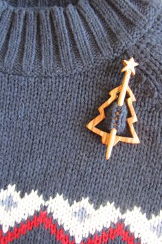 a knitted sweater with a wooden christmas tree brooch on the front and bottom