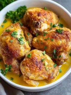 a white bowl filled with cooked chicken and garnished with parsley