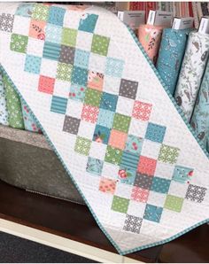 a quilted blanket sitting on top of a wooden table next to bookshelves