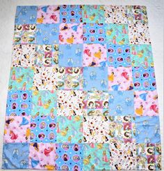 a quilted blanket with princesses and other characters on blue, pink, and white squares