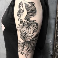 a woman's arm with a black and white tattoo design on the left shoulder